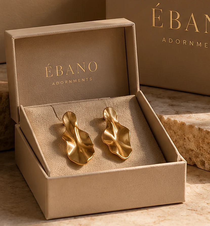 Contemporary sculptural gold earrings in a warm-toned display box